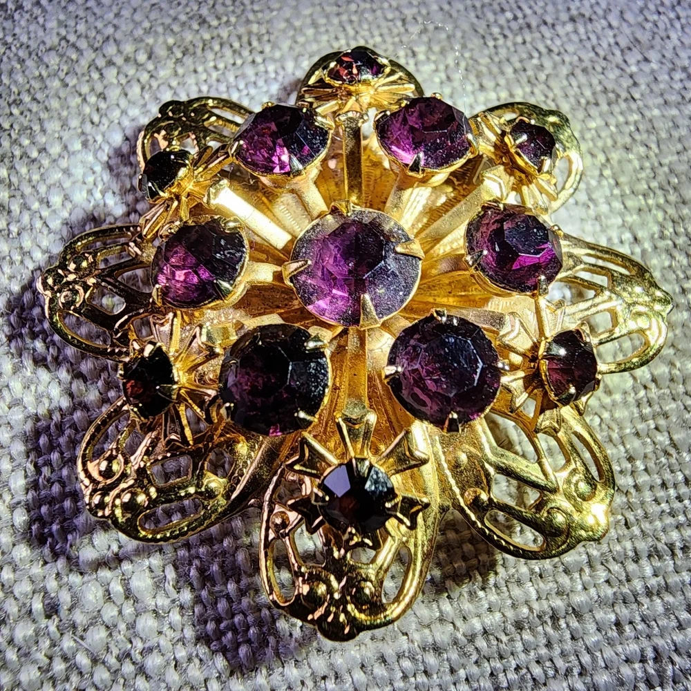 Vintage gold-toned round floral pin/brooch w/ deep violet rhinestones. 1960's